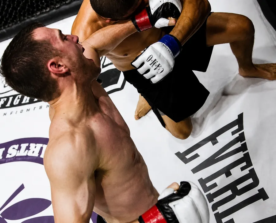 Dean mid-fight inside the cage, throwing a punch at his opponent during his MMA career