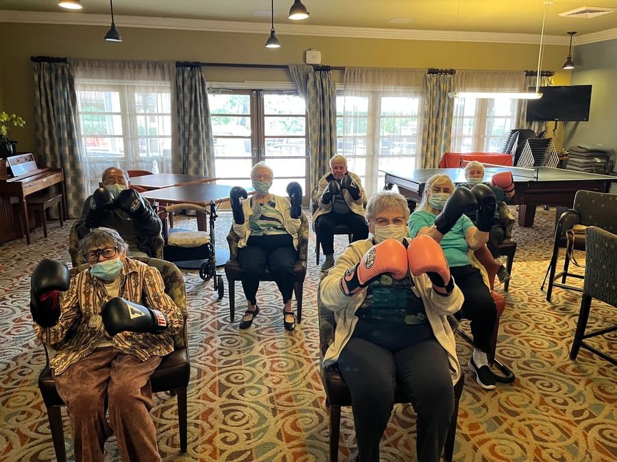 Residents seated with boxing gloves up during a community class